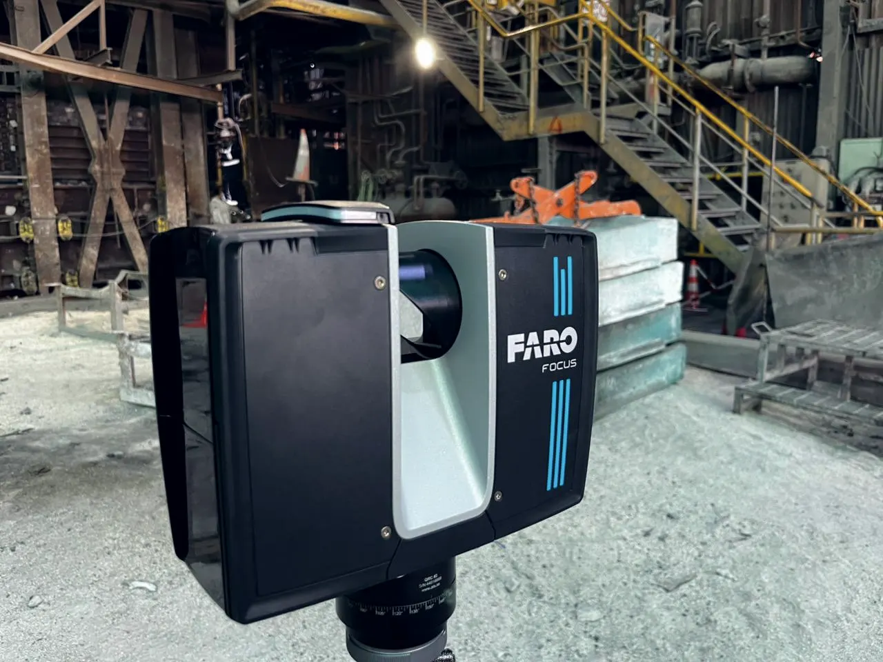 Escáner FARO Focus en primer plano, con estructuras de planta al fondo